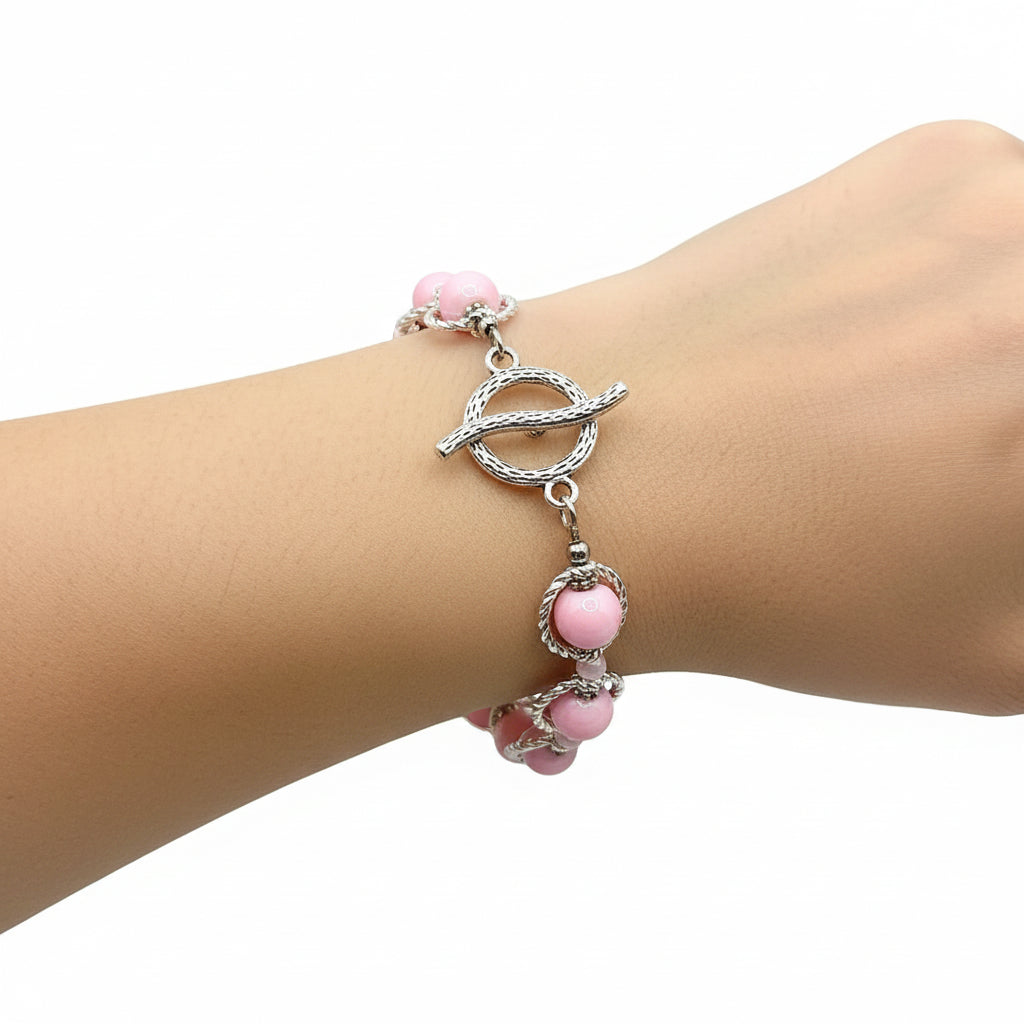 Pink beaded bracelet with gold accents on a blue platform against a dark blue gradient background