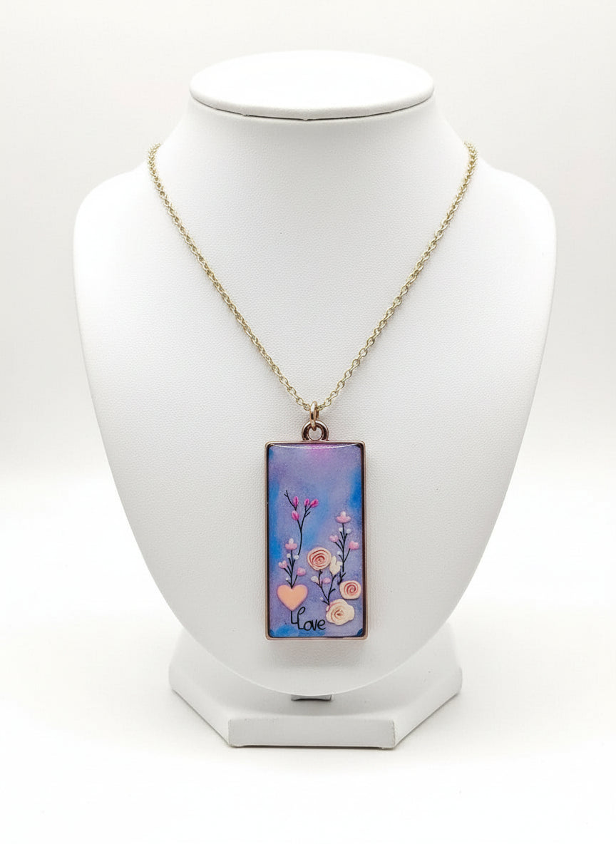 A silver-plated chain necklace with a handcrafted resin pendant featuring a floral pattern and the word 'love'.