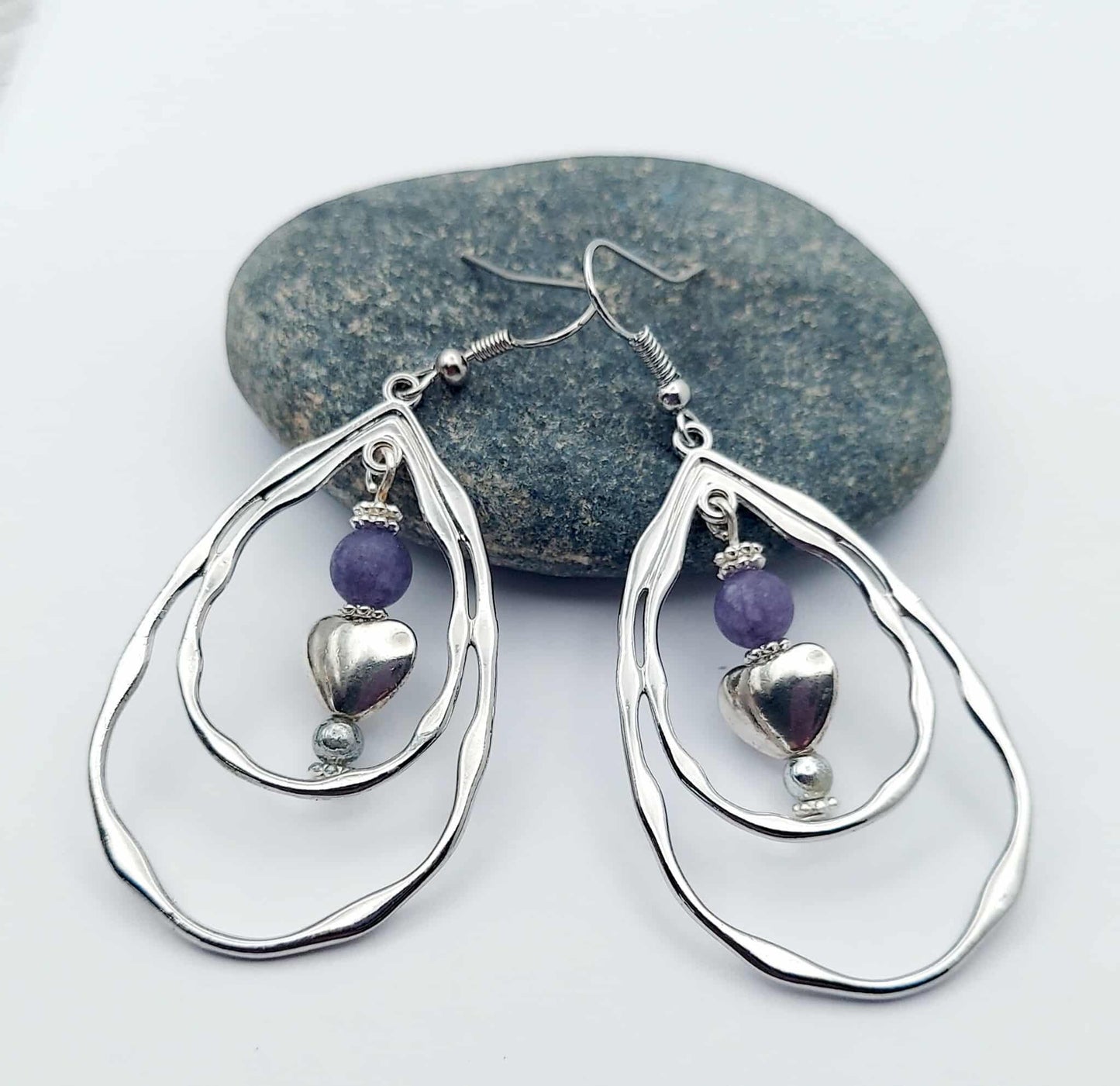 Silver teardrop earrings with purple beads on a white background