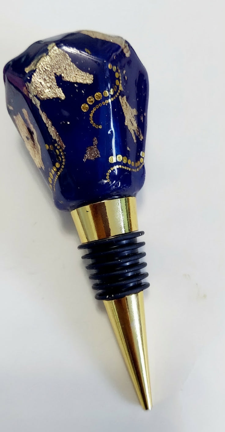 Wine bottle stopper with blue decorative top and gold accents on a white background