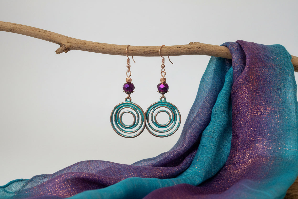 Earrings with purple beads and circular designs held in a hand.