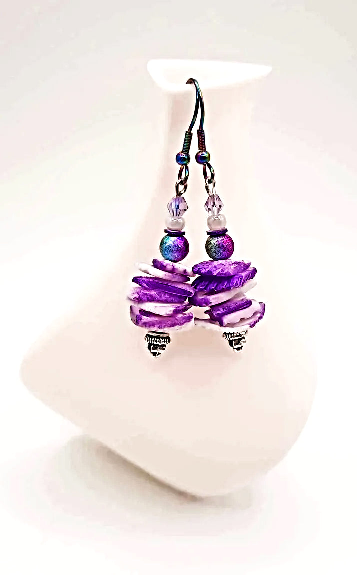 Purple beaded earrings on a white stand with a white background