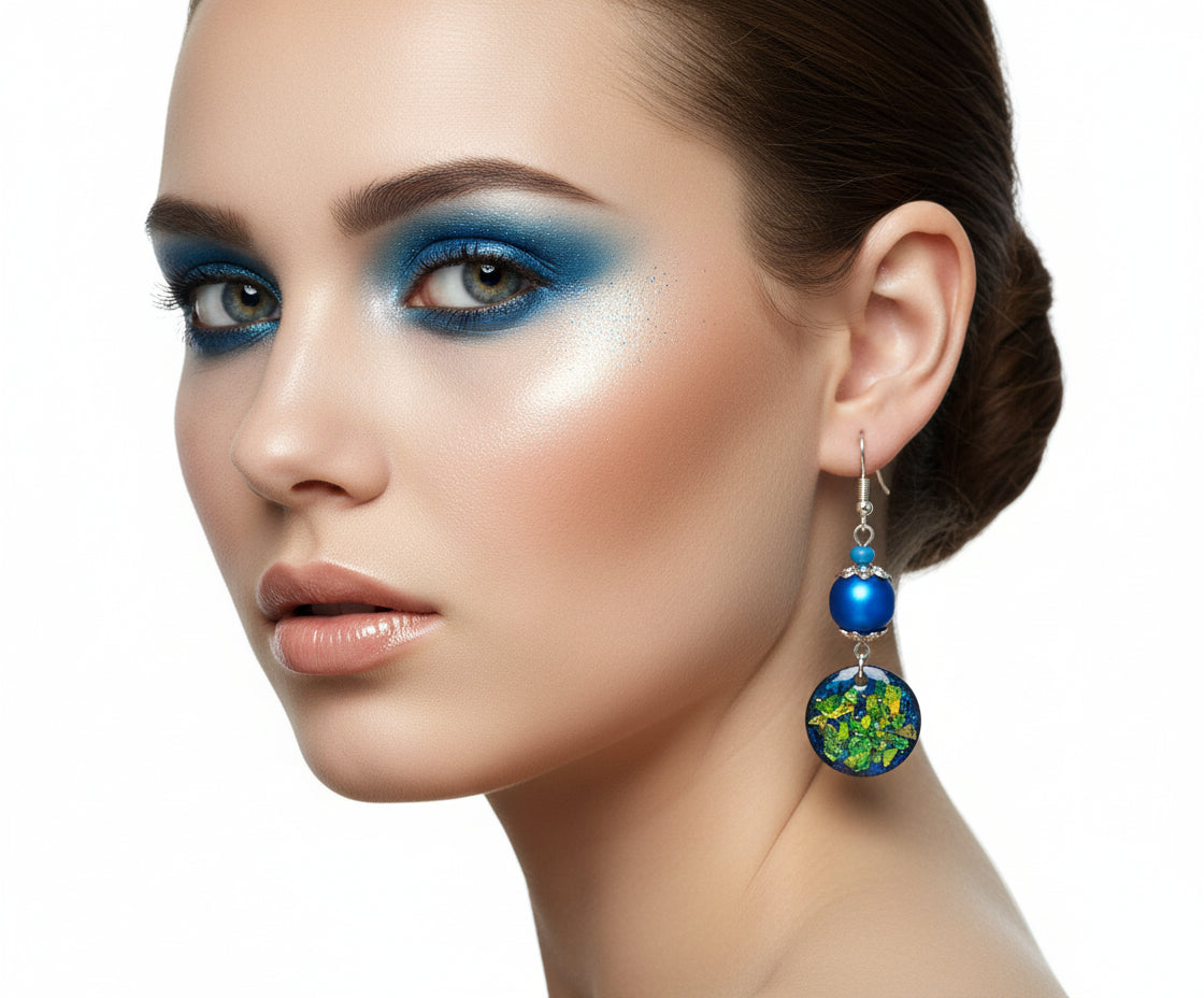 Blue beaded earrings with colorful circular charms hanging on a branch.