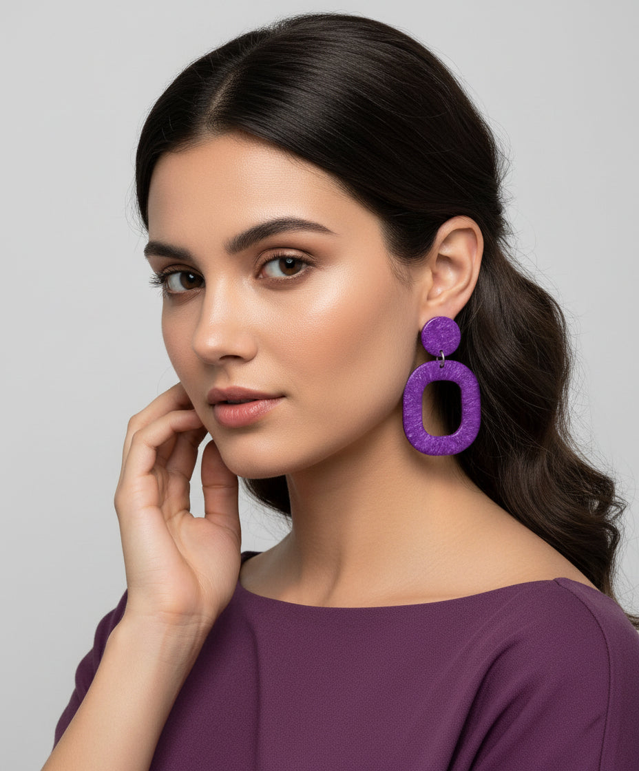 Purple earrings hanging from a branch on a white background