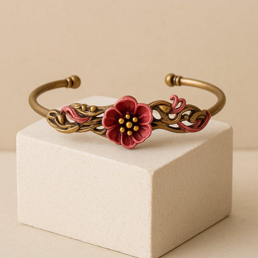 Brass bracelet with a red flower design on a beige stand