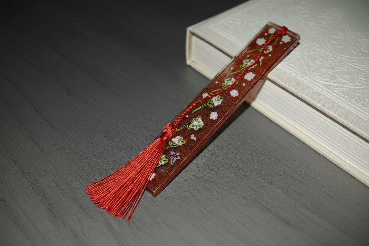 Decorative bookmark with floral patterns and a red tassel on a wooden surface.