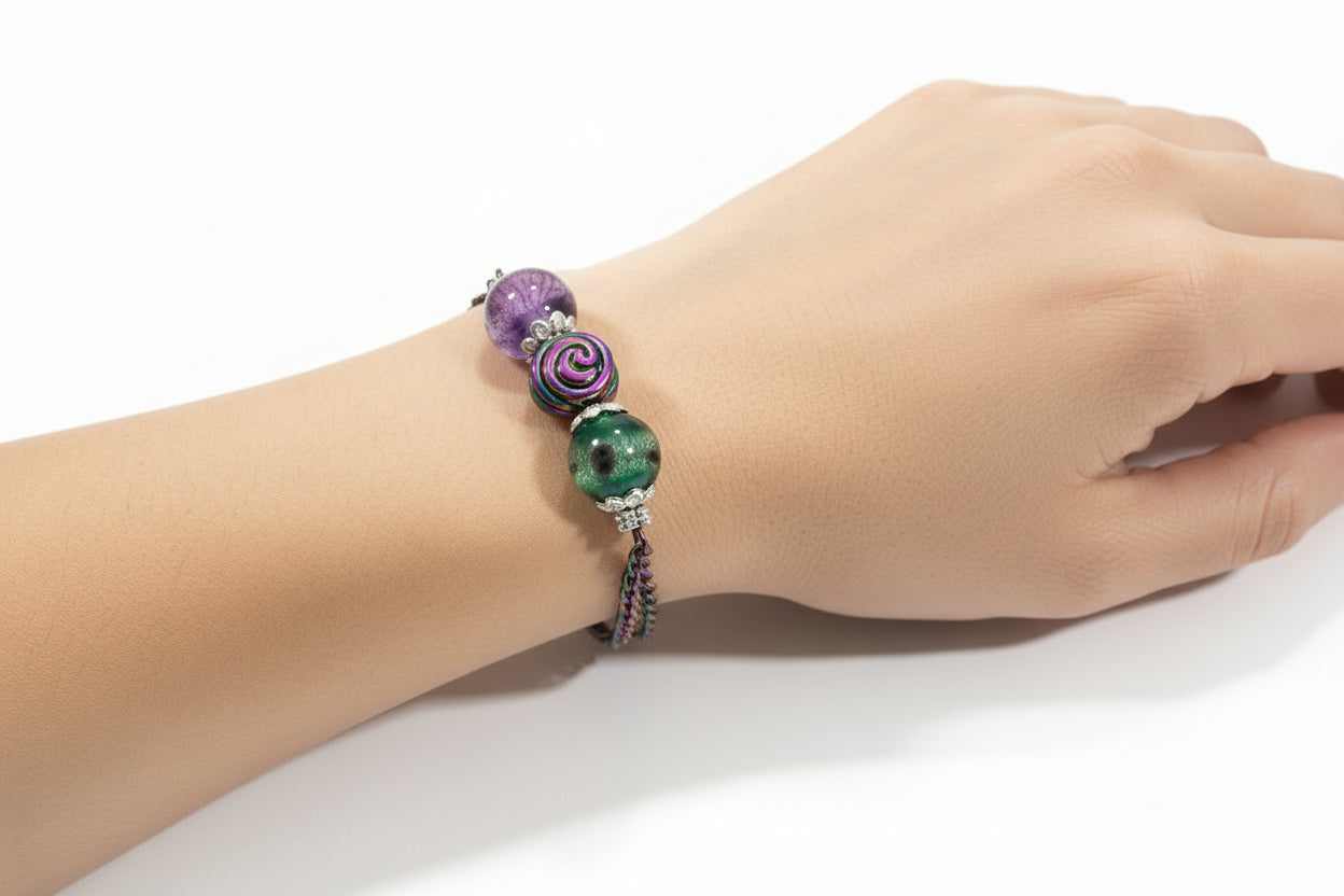 Hand wearing a bracelet with purple and green beads on a white background