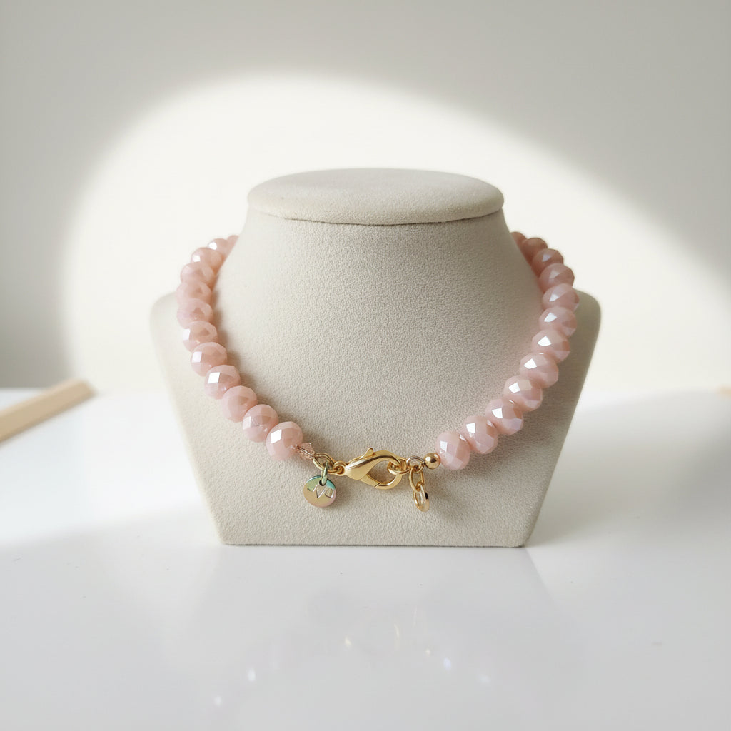 Bracelet with pink beads and gold clasp on a white background