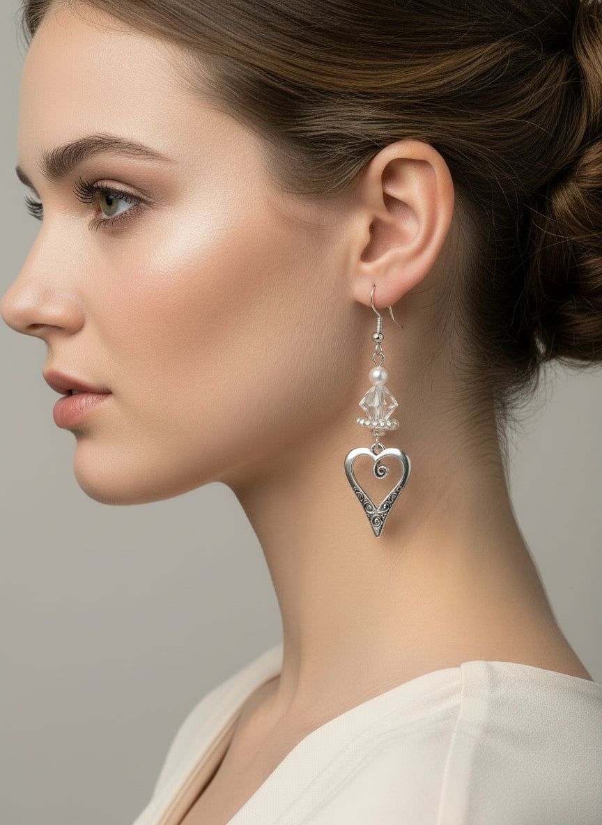 Heart-shaped earrings with clear crystals hanging from a branch on a light background
