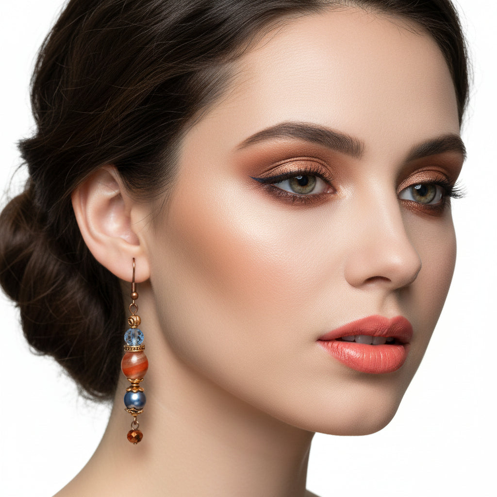 Pair of earrings with blue and orange beads hanging on a branch.