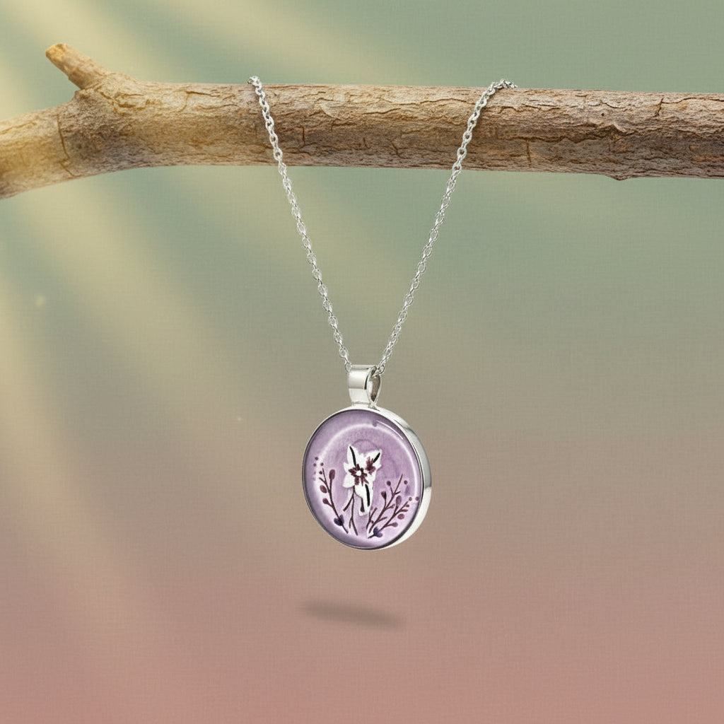 Purple round pendant with floral design on a silver chain against a white background