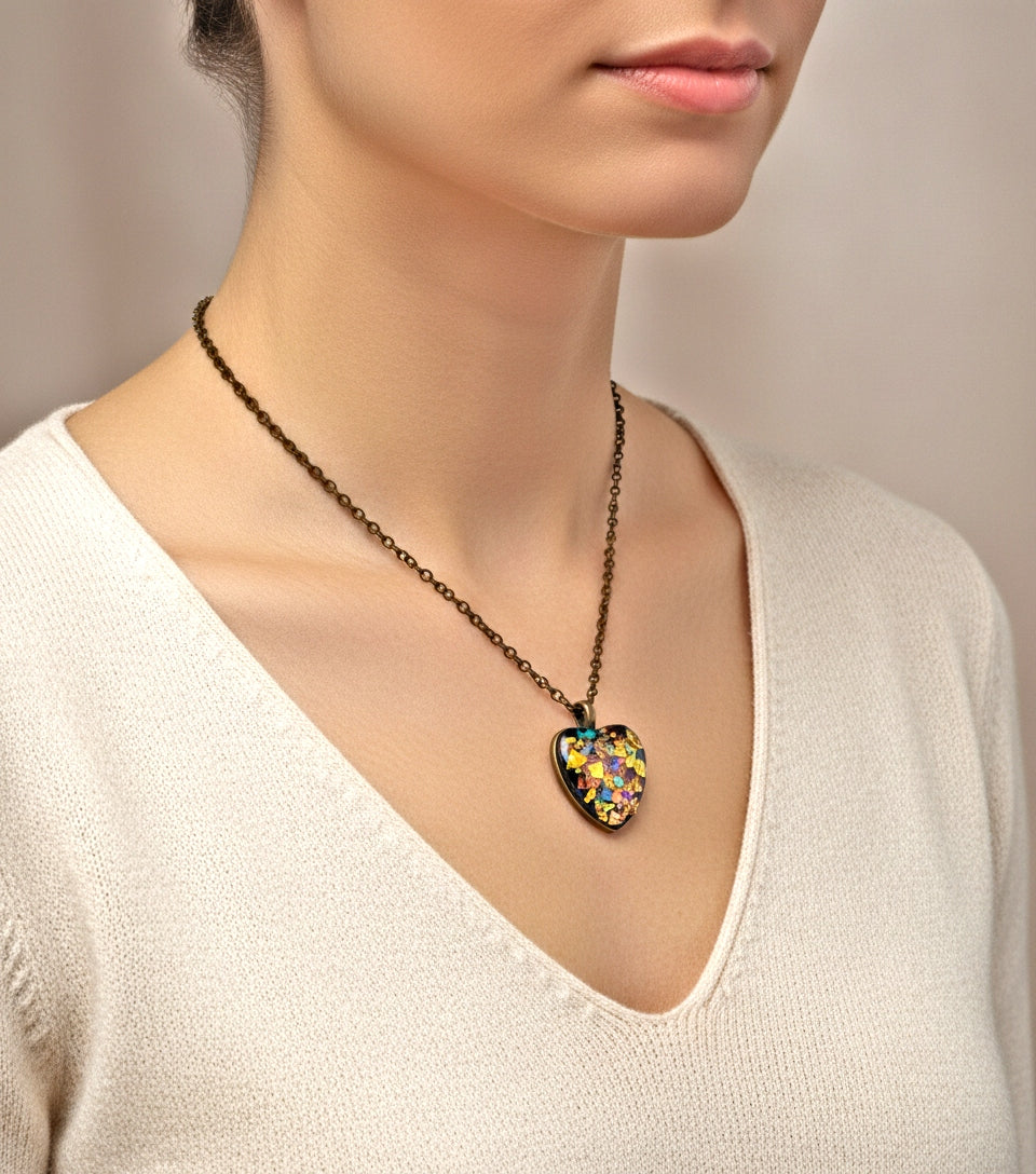 Necklace with a colorful heart-shaped pendant worn by a person in a white sweater.