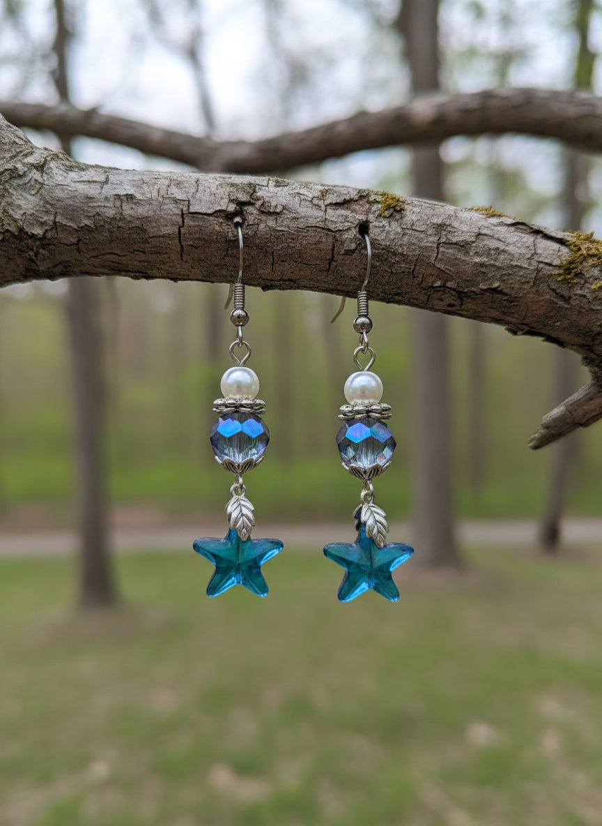 Pair of earrings with blue starfish and beaded design on a dark surface