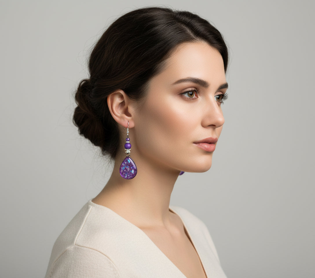 Woman wearing purple teardrop earrings against a neutral background
