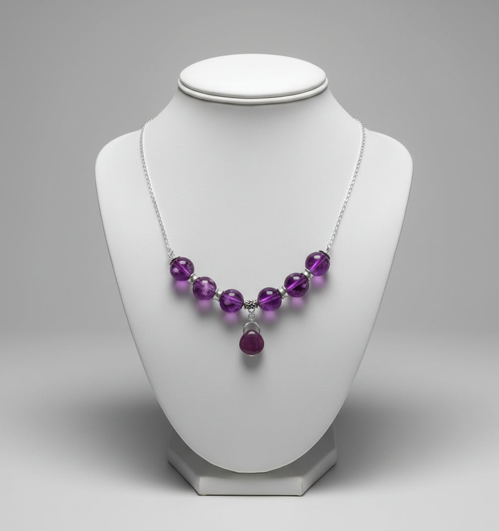 Necklace with purple beads and a heart-shaped pendant on a white surface