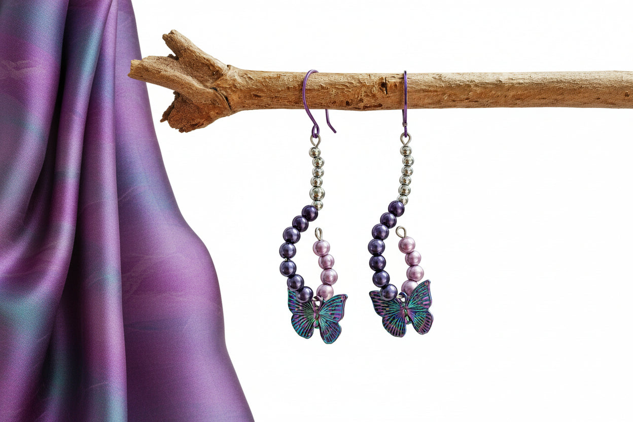 Beaded earrings with butterfly charms on a branch against a blurred natural background