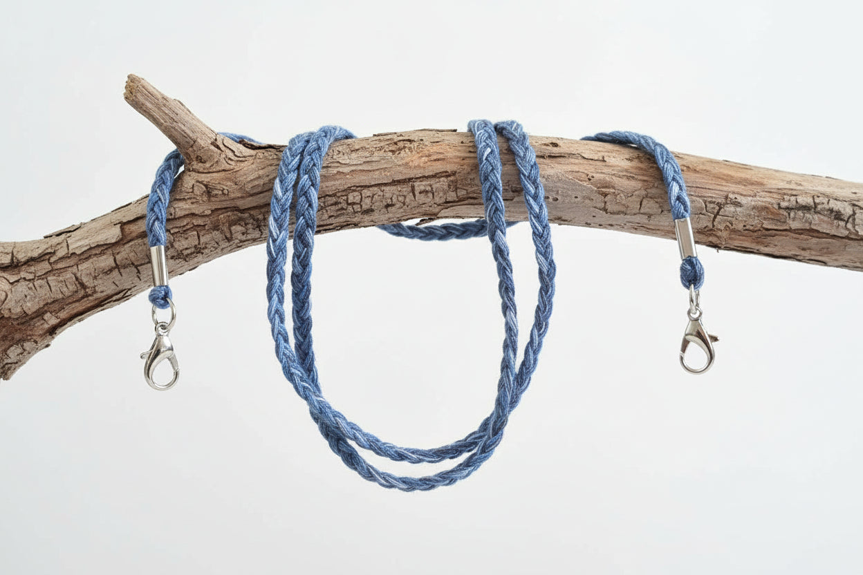Blue braided lanyard with metal clasps on a wooden branch against a white background