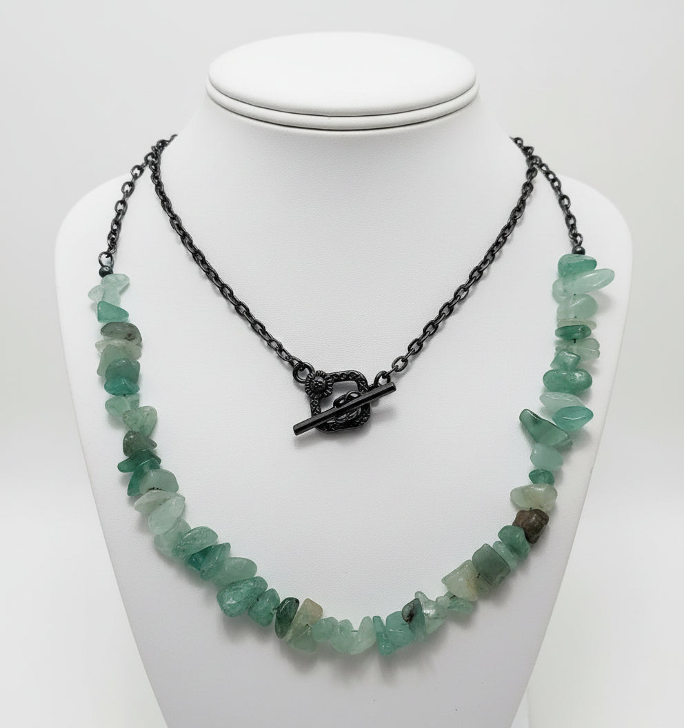 Necklace with green stone beads and black clasp on a white background