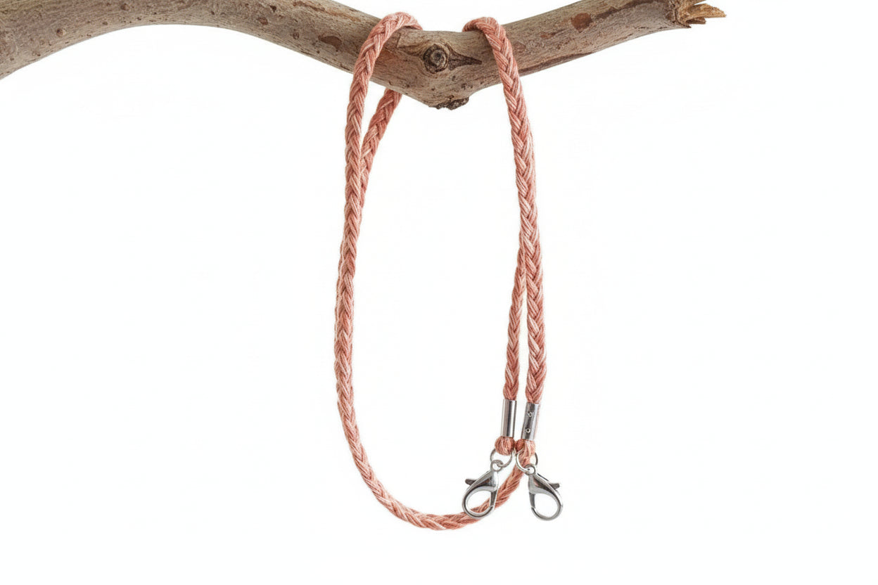 Pink braided leather leash with metal clasps on a white background