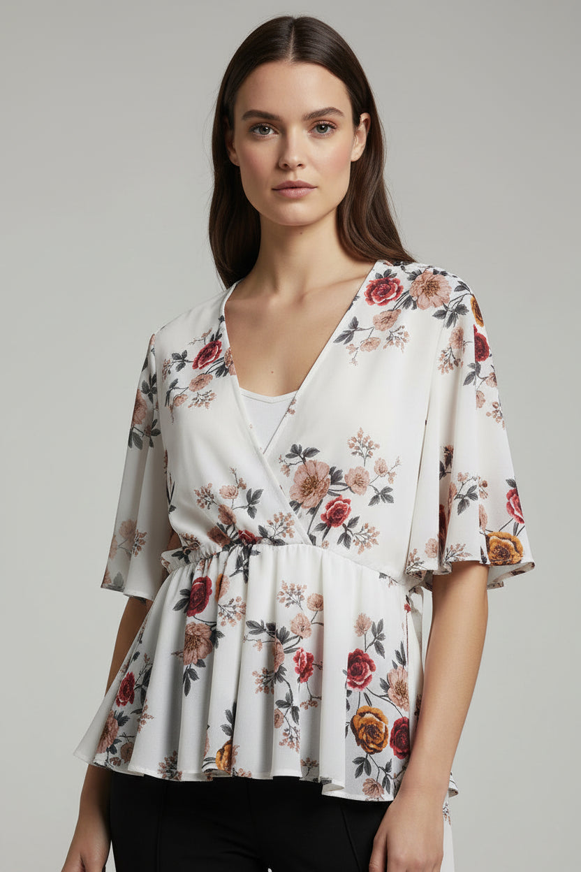 Woman wearing a floral blouse and black pants on a gray background