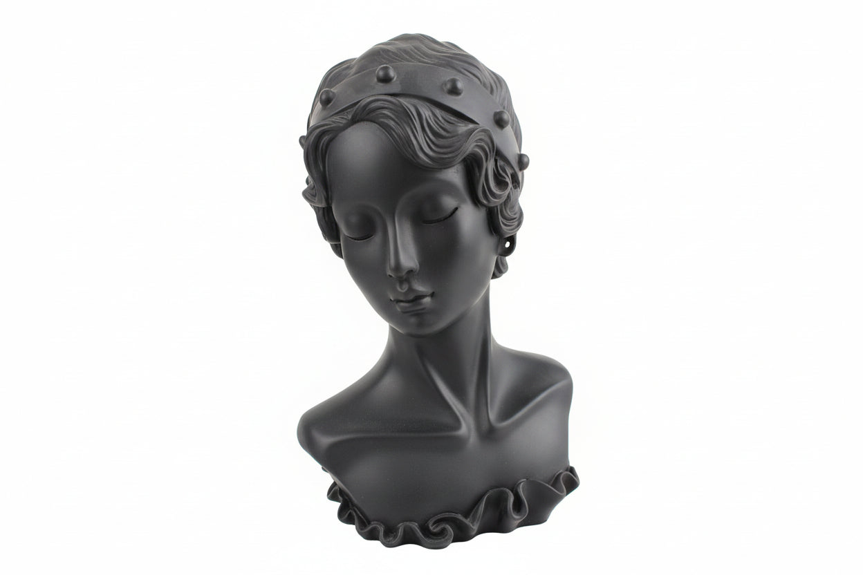 Gray bust sculpture of a woman with decorative headpiece on a surface.