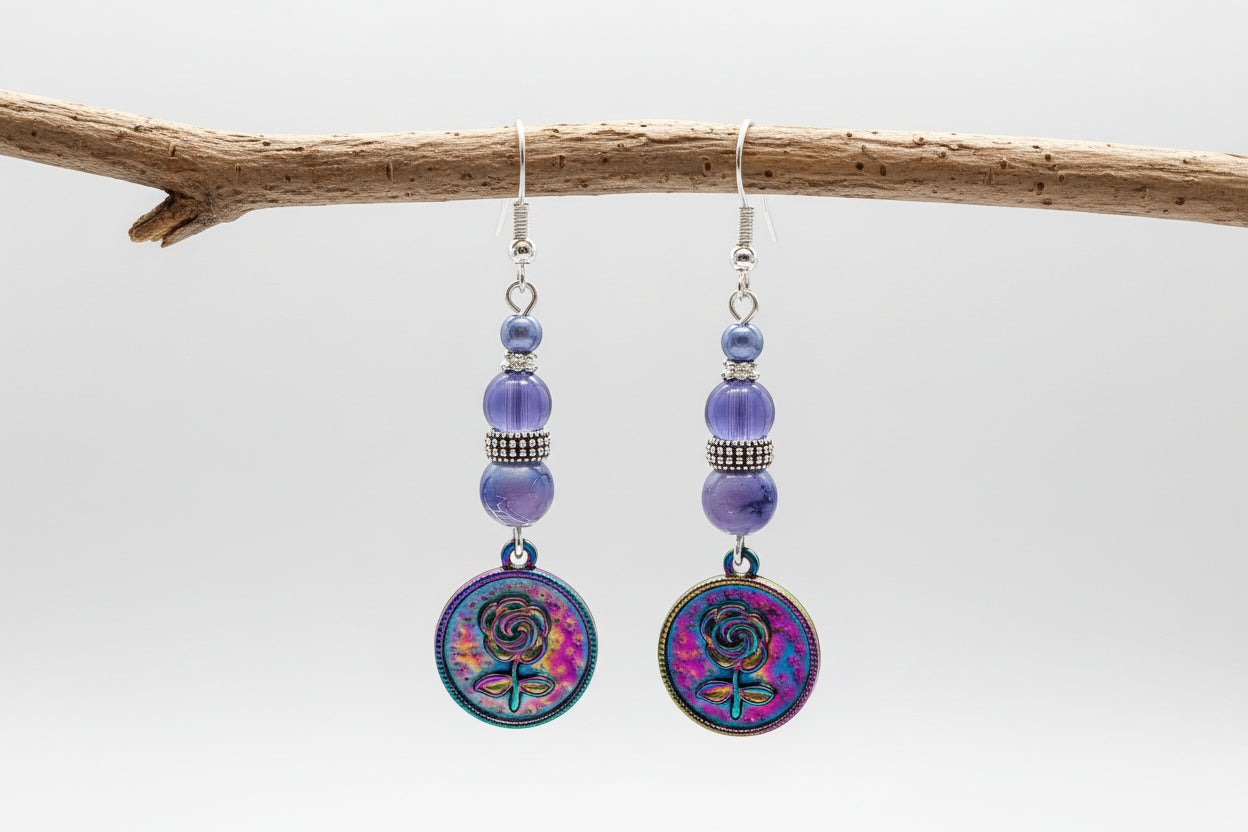 Pair of earrings with colorful circular charms and purple beads on a gray background