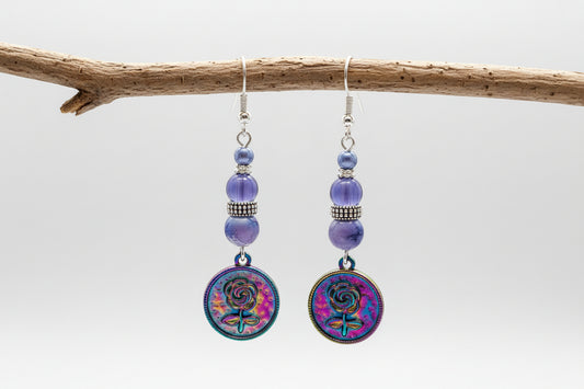 Pair of earrings with colorful circular charms and purple beads on a gray background