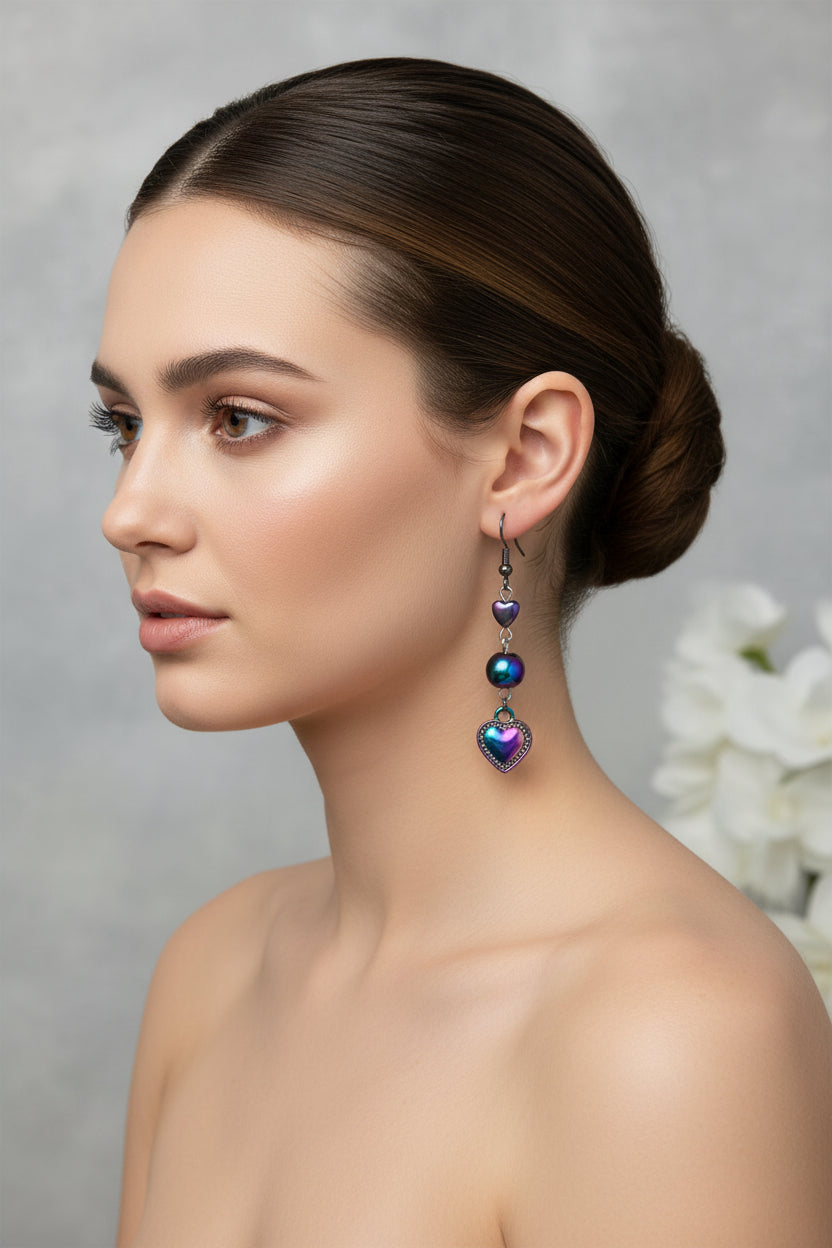 Heart-shaped earrings with colorful beads hanging from a branch on a white background