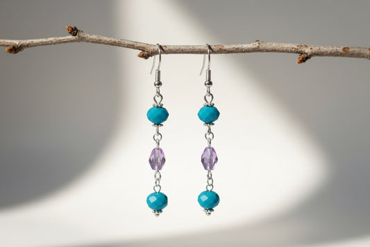 Pair of earrings with blue and purple beads on a light background