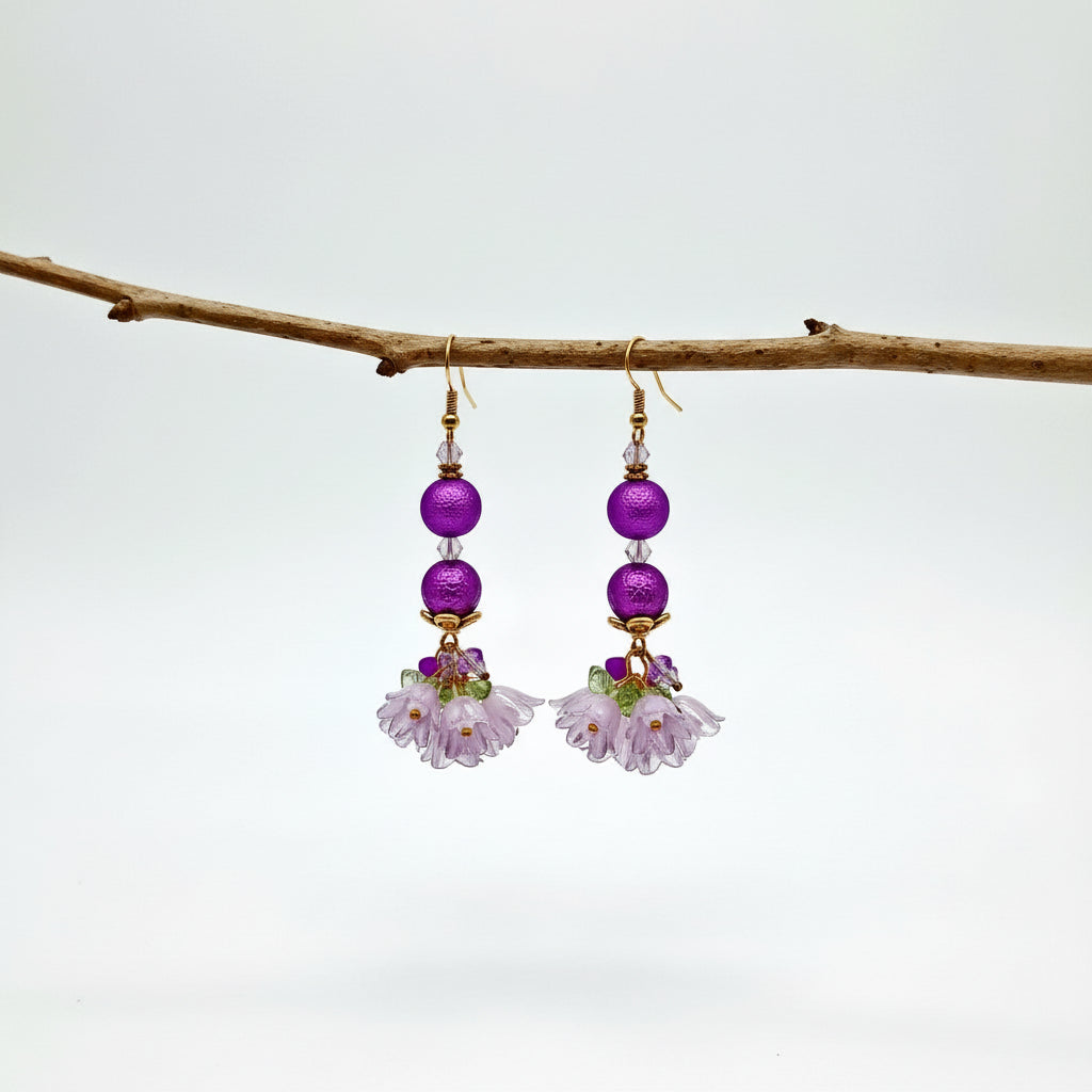 Purple beaded earrings with floral elements hanging on a branch against a light background