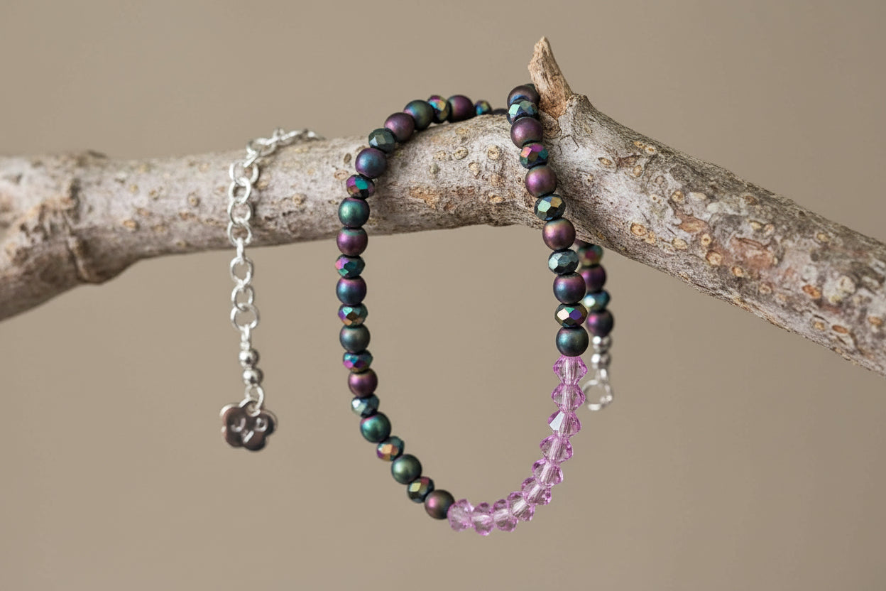 Beaded bracelet with multicolored beads and a pink crystal on a light gray background