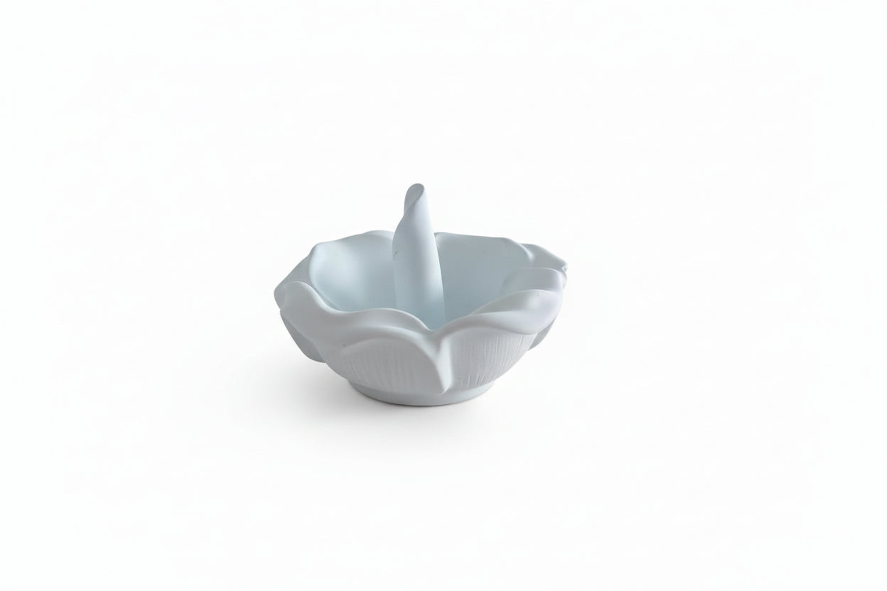 White ceramic ring holder on a beige surface with a blurred indoor background