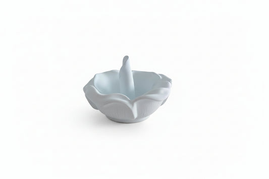 White ceramic ring holder on a beige surface with a blurred indoor background