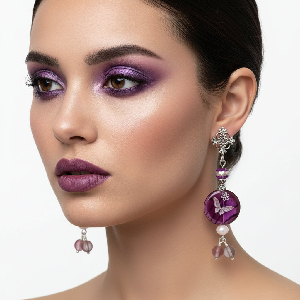 Purple butterfly-themed earrings with pink accents hanging on a branch.