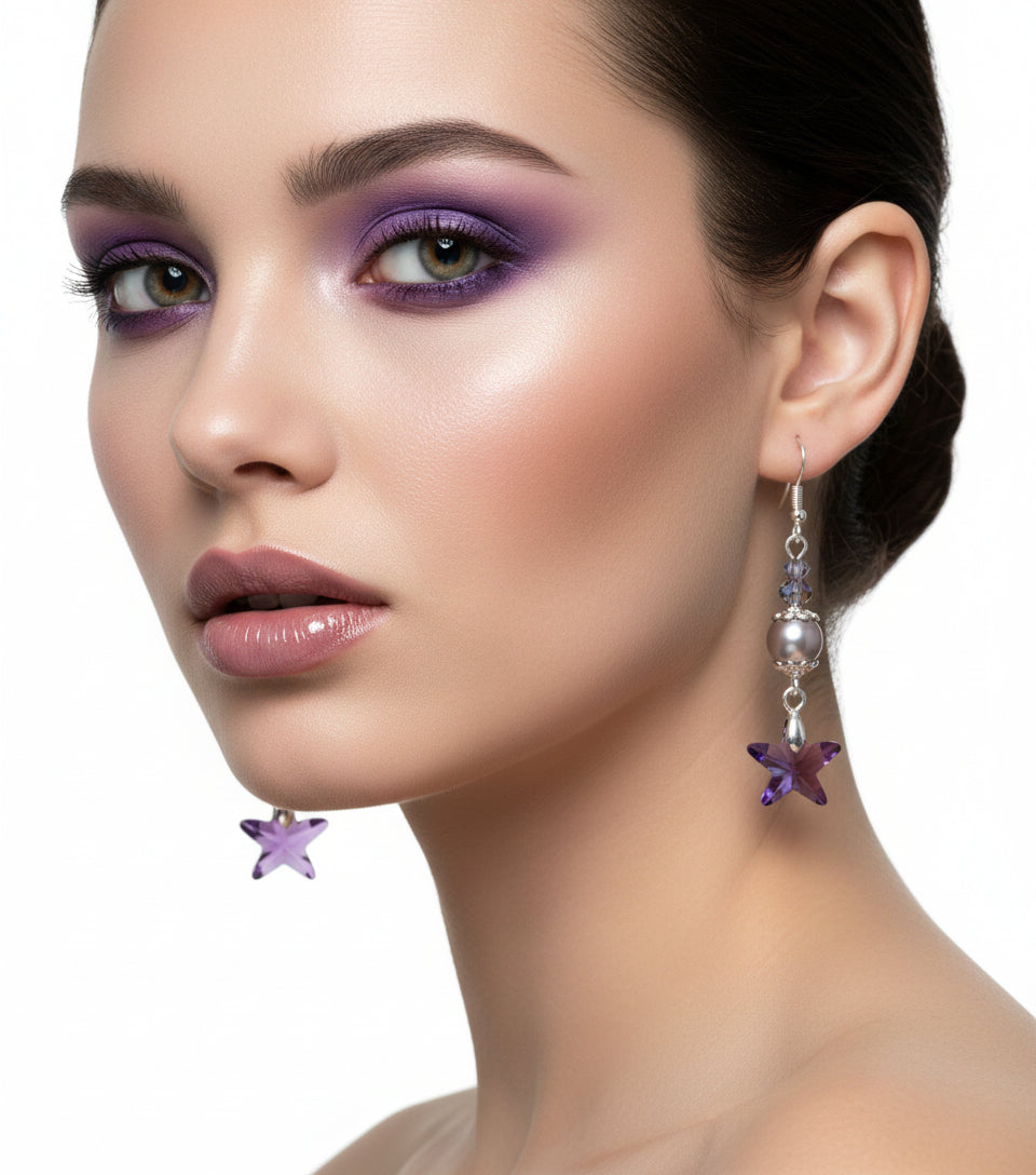 Pair of earrings with star-shaped purple beads hanging from a branch on a white background
