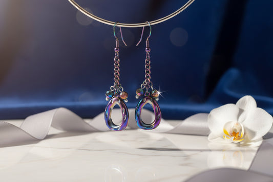 Colorful earrings hanging from a branch against a white background