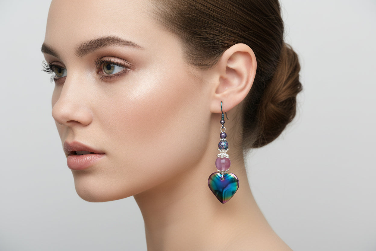 Heart-shaped earrings with colorful beads hanging on a branch against a light background