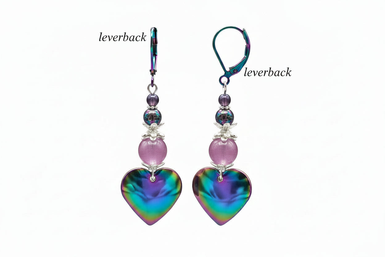 Heart-shaped colorful earrings with purple beads hanging on a branch.