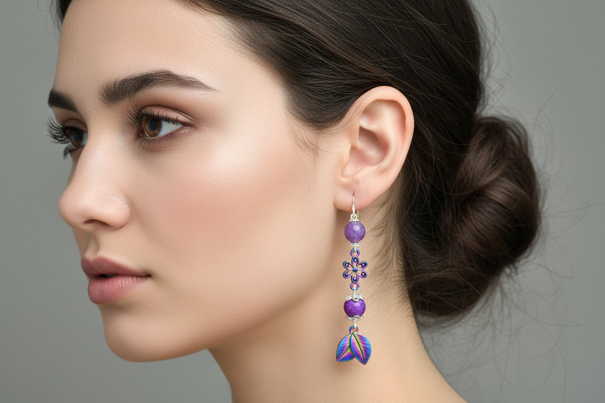 Purple beaded earrings with floral designs hanging from a branch.